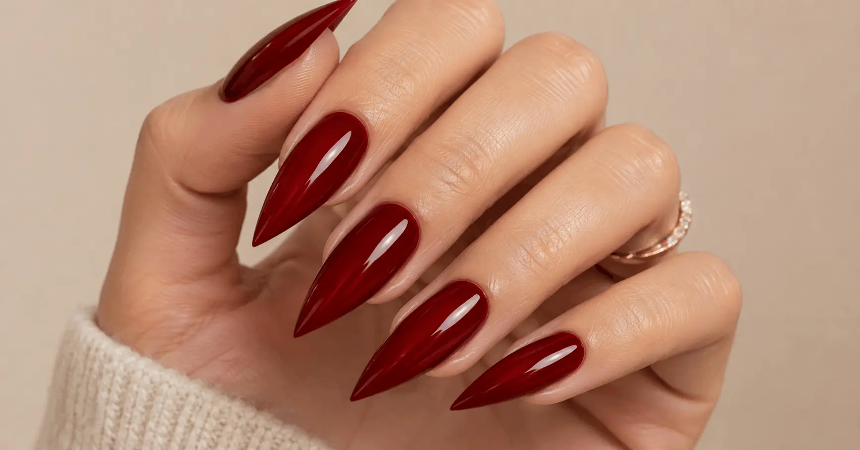 Close-up of a manicured hand with sharp arrowhead-shaped triangle nails in red gel polish